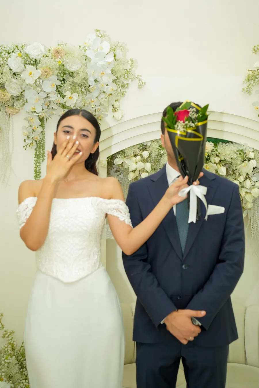 Kübra gülerek Abdullah’ın yüzünü bir buketle kapatıyor